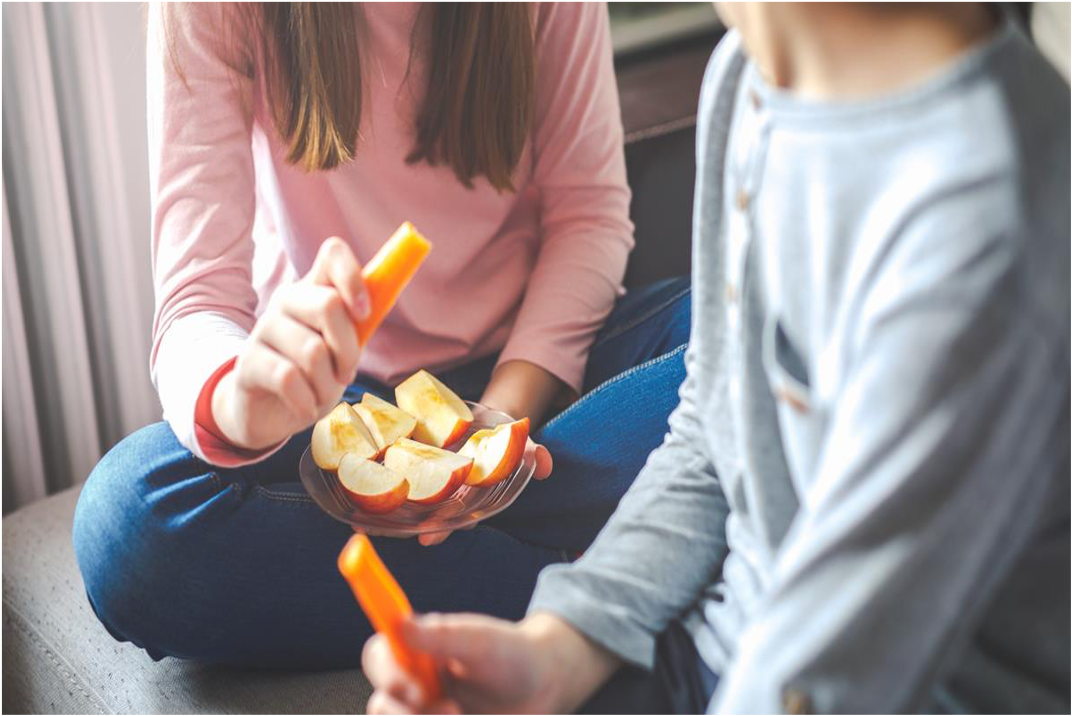Teens eating carrot and apples