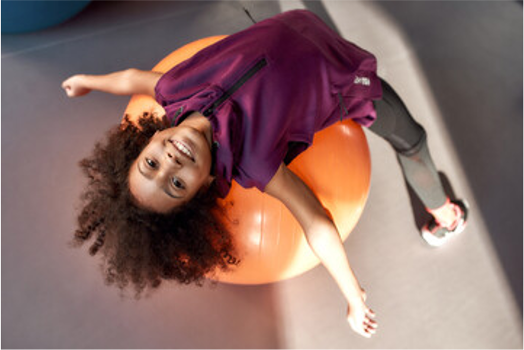 girl stretching on orange yoag ball